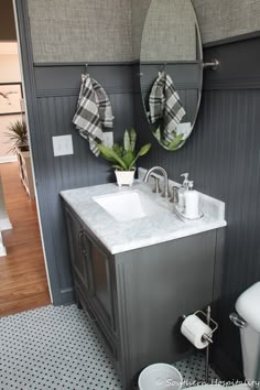 a white sink sitting under a mirror in a bathroom next to a wall mounted toilet