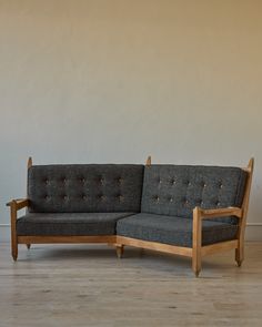 a gray couch sitting on top of a hard wood floor next to a white wall