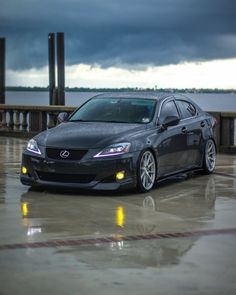 a black car parked in front of a large body of water under a cloudy sky