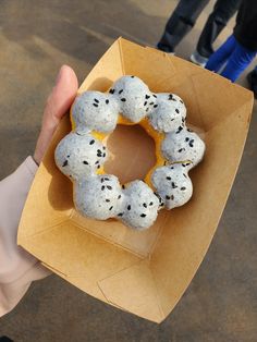 a person holding up a box with some donuts in it's middle,