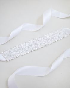 A statement sash is encrusted with beautiful pearls attached on bridal white double-faced satin ribbon. This classic pearly belts creates a romantic finishing touch to your bridal gown, bridesmaids and flower girls, or as hair accessories. DETAIL:Adult Size 108"Kids Size 78"Applique size: 12" length, 2" wideHANDMADE IN USAIMPORTED MATERIALS