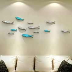 a living room filled with white couches and wall mounted metal fish sculptures on the wall