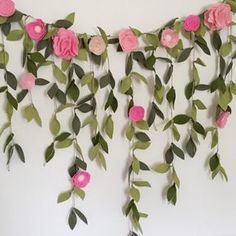 some pink flowers and green leaves are hanging on the wall