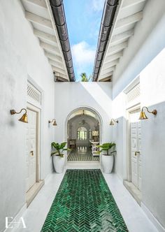 the hallway is decorated in white with green tile flooring and potted plants on either side