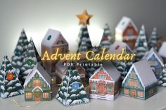 a group of paper houses sitting on top of a white table next to a christmas tree