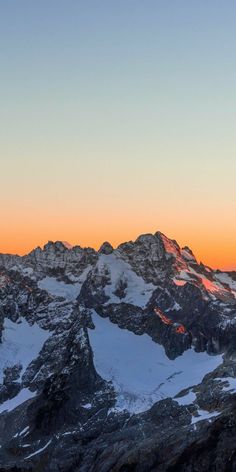 the mountains are covered in snow as the sun is setting over them and there is no image to provide a caption for