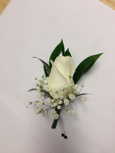 a white rose and baby's breath boutonniere on a piece of paper