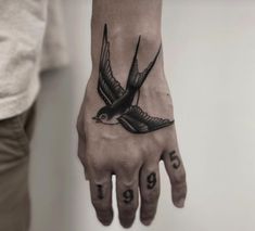 a black and white photo of a hand with a bird tattoo on it's palm