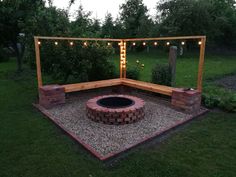 an outdoor fire pit surrounded by lights and gravel in the middle of a backyard area