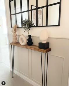 a shelf with some vases and mirrors on it next to a wall mounted mirror