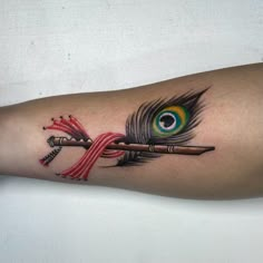 a peacock feather and arrow tattoo on the arm