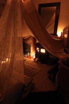 a canopy bed in a bedroom with candles on the floor next to it and a mirror