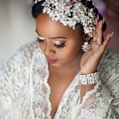 a woman wearing a white dress and headpiece with pearls on it's hair