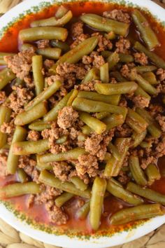 green beans with ground meat and sauce in a white bowl on a woven place mat