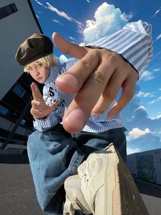 a young boy sitting on top of a skateboard with his hand up to the camera