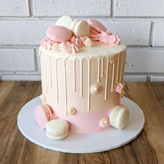 a pink and white cake with macaroons on top