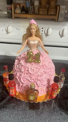 a barbie doll is sitting on top of a cake with pink frosting and gold decorations