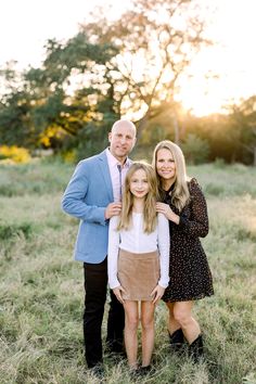 an adult and two children posing for a photo in a field at sunset with the sun behind them