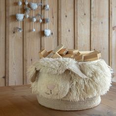 a white sheep basket sitting on top of a wooden table