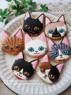 there are many decorated cookies with different cats on the top one is white and has blue eyes