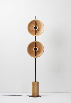 three wooden discs on a black stand with a white wall in the backgroud