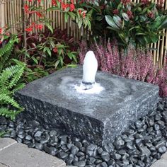 a stone fountain surrounded by plants and rocks