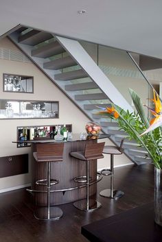 a bar with stools next to a stair case in a living room under a staircase