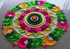 a colorful circular design made with flowers and leaves on a white table cloth, surrounded by other decorative items