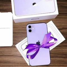 an apple phone with a purple bow on the front, and a white box behind it