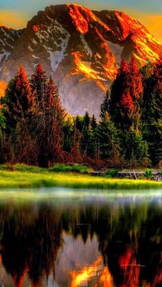 the mountains are reflected in the still water of the lake as the sun goes down