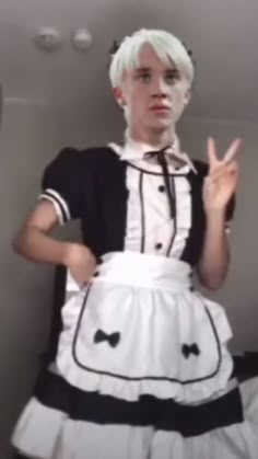 a woman with white hair wearing a black and white dress is making the peace sign