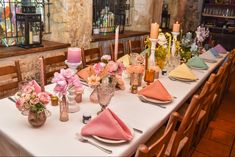 a table set with flowers and candles for a wedding reception in a stone walled room