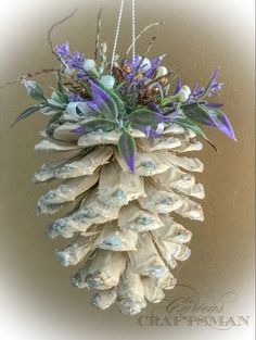 a pine cone hanging decoration with purple flowers