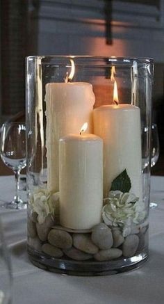 three white candles are sitting in a glass vase