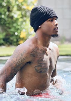 a shirtless man in the water wearing a beanie