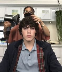 a woman blow dries her hair in the kitchen