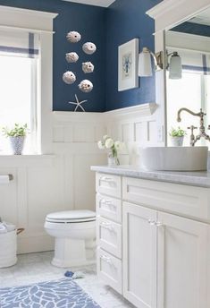 a bathroom with blue walls and white cabinets is pictured in this image, there are flowers on the counter next to the toilet