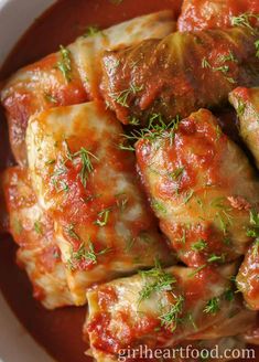 stuffed cabbage rolls with marinara sauce in a white bowl