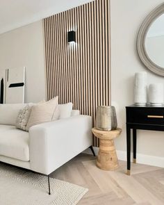 a living room with a white couch and wooden paneled wall next to a black table