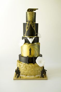 a three tiered cake with black, gold and white designs on it's sides