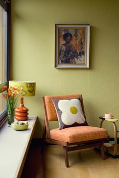 a chair sitting in front of a window next to a table with flowers on it