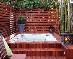 a hot tub sitting on top of a wooden deck next to a bamboo planter