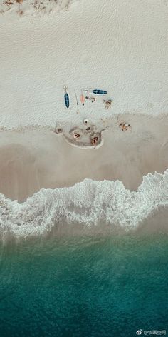 an aerial view of the beach and ocean with boats parked on it's shore