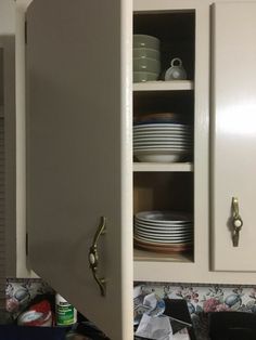 an open cabinet with plates and bowls in it