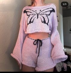 a woman wearing a pink sweater and shorts with a butterfly drawn on the side of her shirt