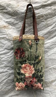 a handbag with flowers on it sitting on top of a white cloth covered bed