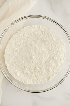 a glass bowl filled with flour on top of a white counter