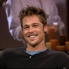 a man smiling while sitting down in front of a tv screen with candles on it