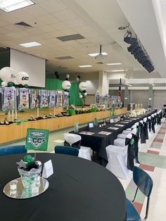 tables and chairs set up in a large room with pictures on the wall behind them