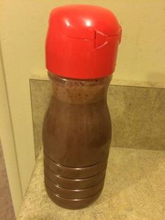 a brown and red plastic bottle sitting on top of a tile floor next to a wall